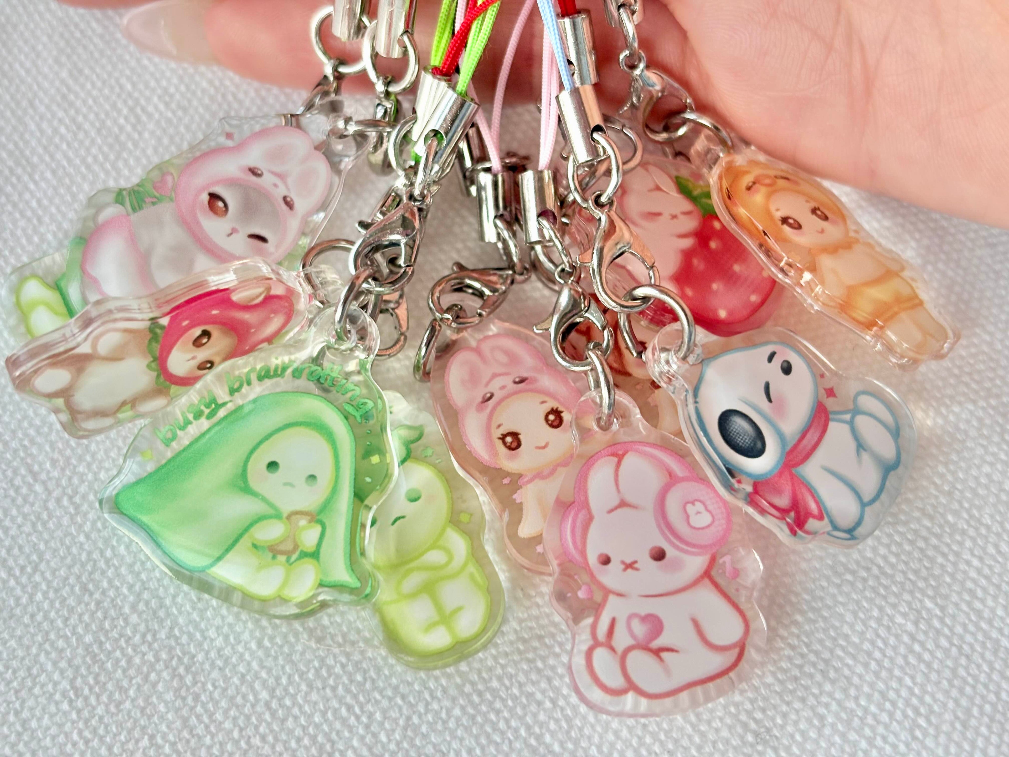 Set of colorful cartoon character keychains held by a hand on a light background